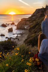 Rear view of young women watching sunset up in the hills in El Matador Beach, Malibu, California