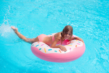 Pretty little girl swimming in outdoor pool and have a fun with inflatable circle