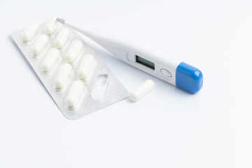 The thermometer with a package of pills and capsules on a white background with space for text