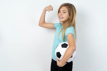 Portrait of powerful cheerful beautiful caucasian teen girl wearing sportswear holding a football...