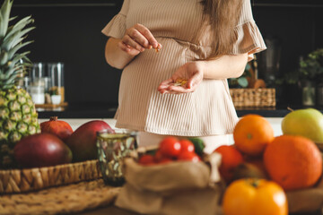 Pregnant woman holding glass of water and vitamins, healthy pregnancy concept