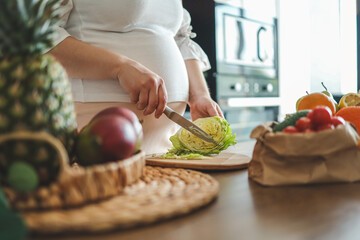 Pregnant woman making salad in her kitchen, healthcare