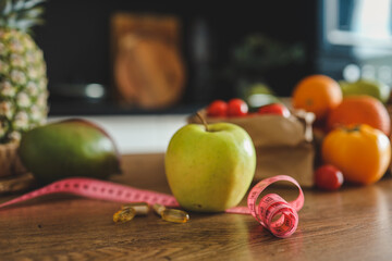 Green apple, vitamins and meter on the kitchen table, weight loss concept