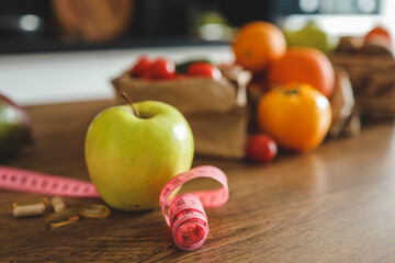 Green apple, vitamins and meter on the kitchen table, weight loss concept