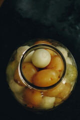 Conserva de cebolas e batatas no pote de vidro em tons escuros vista de cima