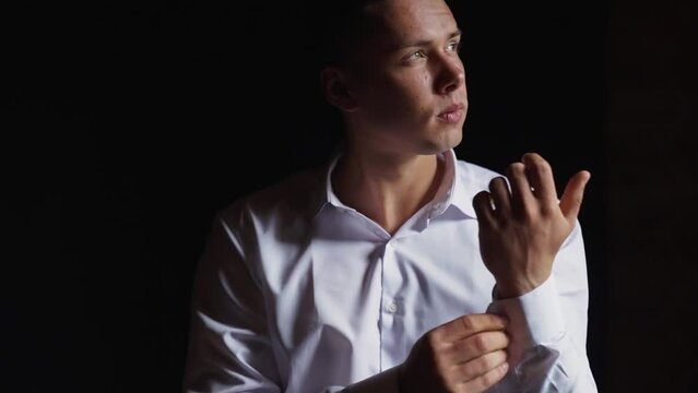 Portrait of a chic guy in a white shirt in a dark interior. Sexy man near window