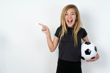 beautiful caucasian teen girl wearing sportswear  over white wall points aside on copy blank space. People promotion and advertising concept