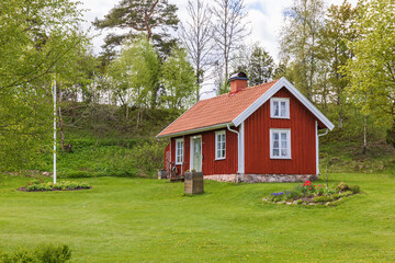 Fototapeta na wymiar Red idyllic old cottage with a garden