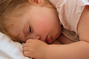 Peaceful adorable baby sleeping on his bed at home. Sleeping newborn baby concept. One year old baby girl sleeps peaceful at domestic room interior background. Serene dream. Cute Face Close Up