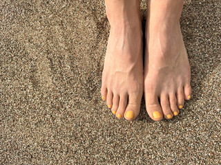 The girl put her feet together on the sand in a golden sunset