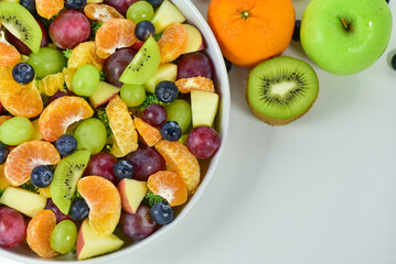 Healthy fresh fruit salad bowl on white background. Top view. Healthy food concept, healthy high vitamin fruit, mixed fruit background.