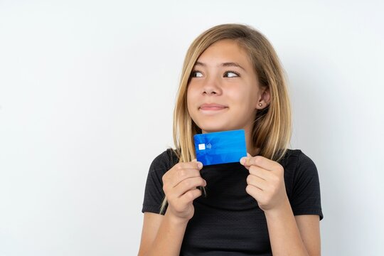 Photo of cheerful beautiful caucasian teen girl wearing sportswear  over white wall hold debit card look empty space