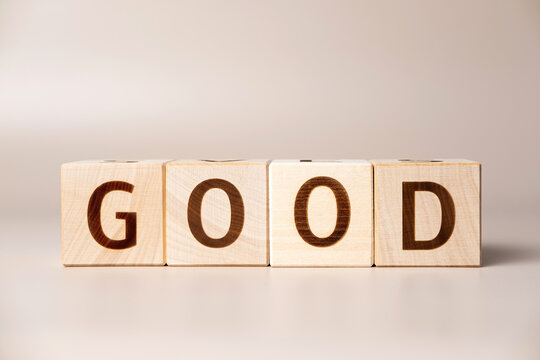 The word GOOD on wooden cubes on a beige neutral studio background. Copy Space. Written. Text words matter. Conceptual Photo. Positive approval symbol. Volume increase business grow concept