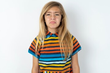 beautiful caucasian teen girl wearing striped T-shirt over white wall crying desperate and depressed with tears on his eyes suffering pain and depression. Sad facial expression and emotion concept.