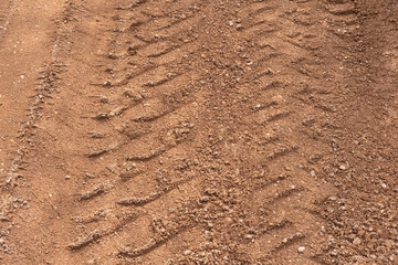 Footprint of car tire tread in a sand gravel road texture. Country road textured background. Backdrop for various ideas. Small stones land. Abstract sandy rough surface. Trendy effect. No people. Tyre