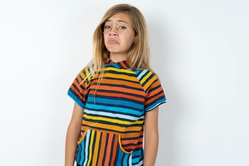 beautiful caucasian teen girl wearing striped T-shirt over white wall with snobbish expression curving lips and raising eyebrows, looking with doubtful and skeptical expression, suspect and doubt.