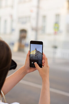 Woman traveler takes pictures the sights while walking through the streets of a European city. Phone, smartphone, hands. Journey. Takes a photo on your phone. Smartphone screen. Traveling lifestyle