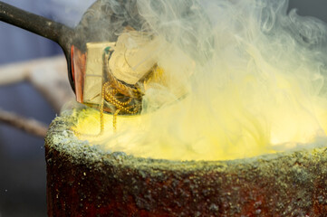 Old rural local Melt Gold pour into ingot mould. Pouring liquid gold into graphite casting form...