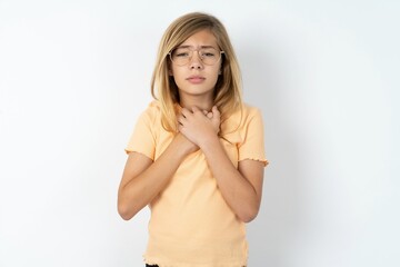 Sad beautiful caucasian teen girl wearing orange T-shirt over white wall feeling upset while...