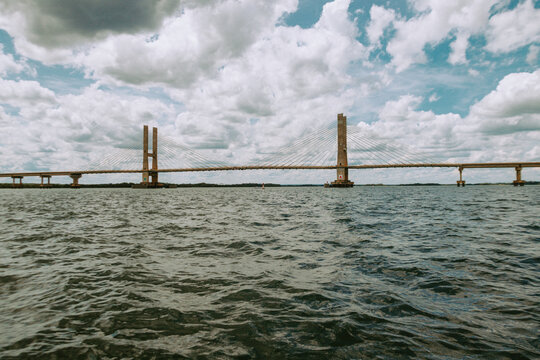 Ponte estaiada com c&eacute;u azul, nuvens e rio com pequenas ondas