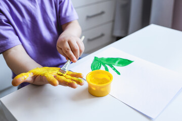 Children's art workshop, the child makes a handprint with paints