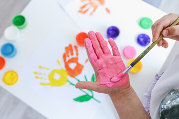 Children's art workshop, the child makes a handprint with paints