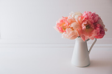 Beautiful bouquet of fresh coral peony flowers in full bloom in vase. Floral still life with blooming peonies. Negative space for text.