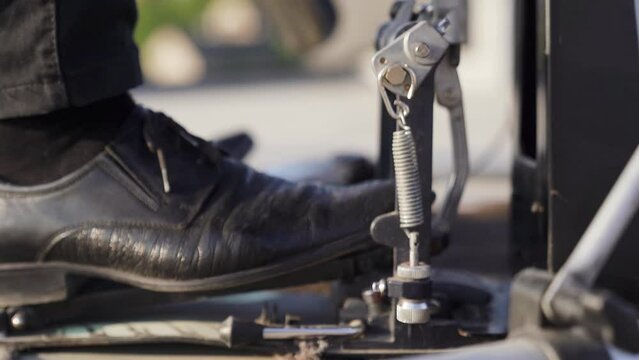 Close-up of man drummer leg in black shoes hitting bass drum with pedal