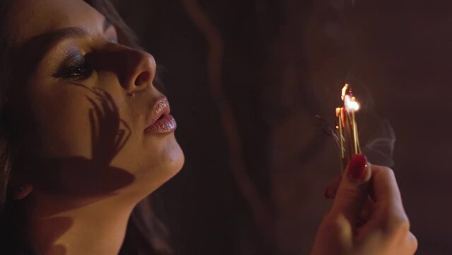 The witch conjures in a dark room, saying a plot by candlelight, close-up 4k