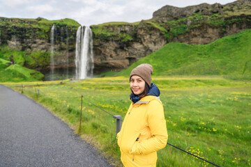 Naklejka premium Asian tourist woman standing at front of Seljalandsfoss waterfall in summer