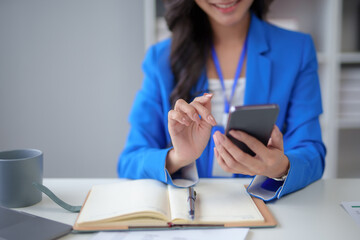 Fototapeta premium Close-up of a woman using a smartphone to work on various application including mobile transaction to send messages, LINE, and various business information sent via social media.