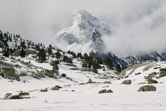 Amazing landscape of massive snowy mountains with high peaks under cloudy sky
