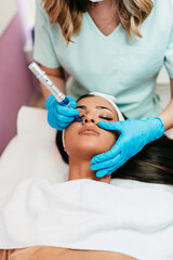 Professional cosmetologist making mesotherapy injection with dermapen on face for effective skin...