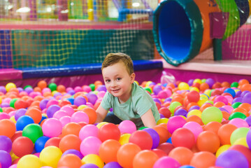 Fototapeta na wymiar Child on the playground with colored plastic balls