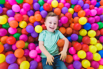 Happy child playing and having fun in kindergarten with colorful balls