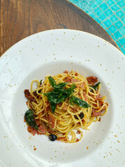 A plate of spaghetti aglio olio in the table on the edge of pool side