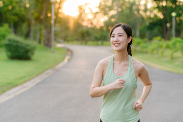 Fit Asian young woman jogging in park smiling happy running and enjoying a healthy outdoor lifestyle. Female jogger. Fitness runner girl in public park. healthy lifestyle and wellness being concept
