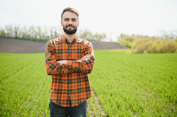 Portrait of farmer in wheat field. A handsome farmer or agronomist is working in the field