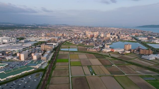 Aerial view of plowed fields in farms by edge of city at golden hour