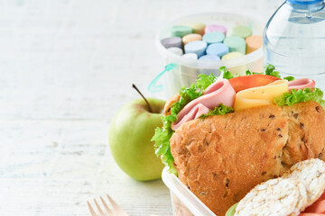 Healthy food for school lunch concept. Healthy bread, meat sandwich with cheese, apple, fresh cucumber, carrots, nuts in container, water and yogurt on kitchen background. Back to school concept.