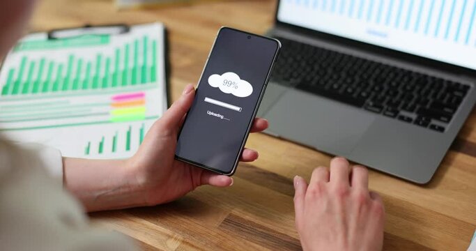 Businesswoman working at computer and holding phone with 99 percents full memory on cloud closeup 4k movie slow motion. Storage of information on cloud concept 