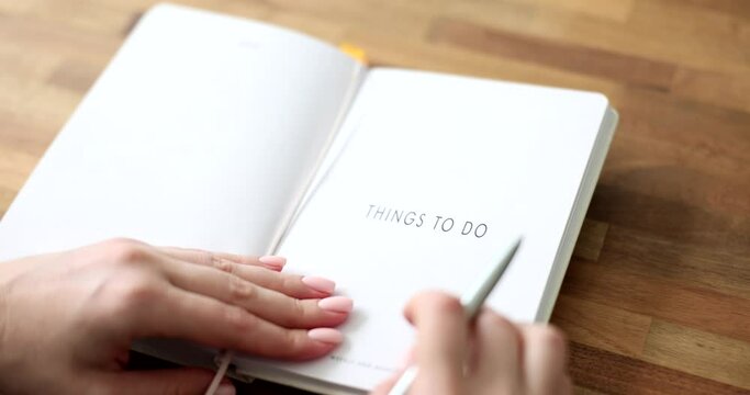 Female hands opening diary and writing down things to do closeup 4k movie slow motion. Planning and organization of affairs concept 