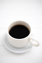 A cup of black aromatic coffee on a wooden background. Coffee for breakfast in a white cup