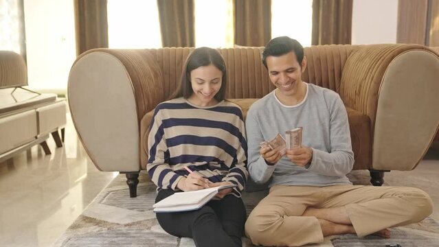 Happy and rich Indian couple counting money and doing future planning