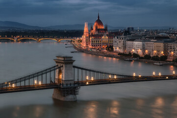 Fototapeta na wymiar The magnificent Hungarian Parliament building on the banks of the Danube River. The majestic monumental building at night. Beautiful lighting.