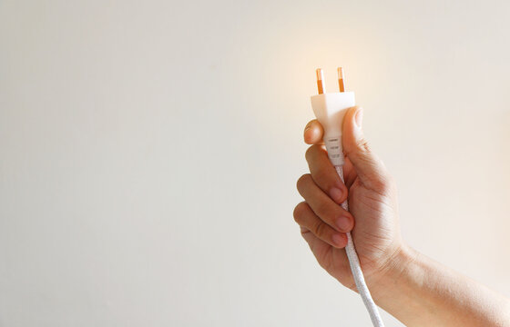 Male hand holding electric wire on white background ,Under the concept of careful use of electricity