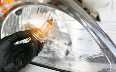 Car mechanic replace the damaged car light bulb and insert the new one. ,Under the concept of...