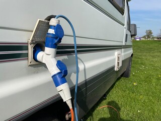 An adaptor to take two electric hook up leads has been plugged into a motorhome recreational vehicle's external electric socket.Leads can be seen coming out of device.Splitter.Dual - obrazy, fototapety, plakaty