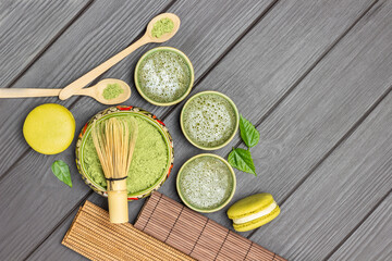 Bamboo whisk in bowl with matcha powder. Matcha green tea, macaroni cakes and wooden spoons on table.