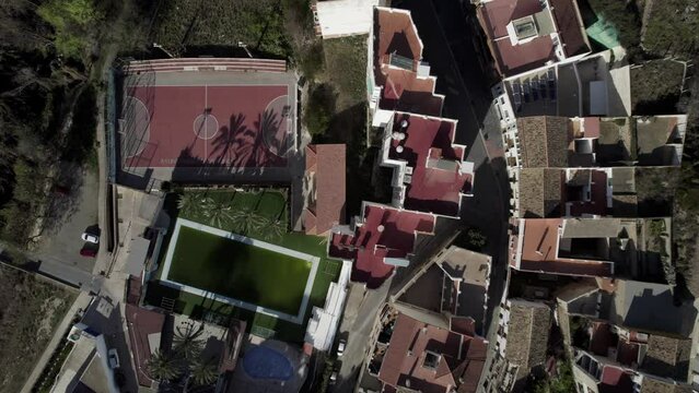 Aerial view of basketball field close to a pool with palms, and buildings, Bunol, Valencia, Spain.